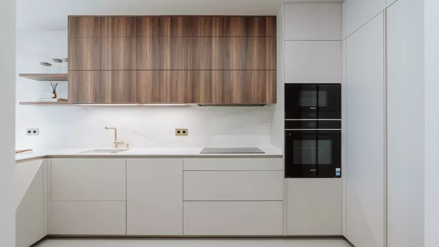 Descubre una cocina abierta con madera nogal y blanco cálido, barra integrada y diseño contemporáneo. Un proyecto real elegante, funcional y luminoso.