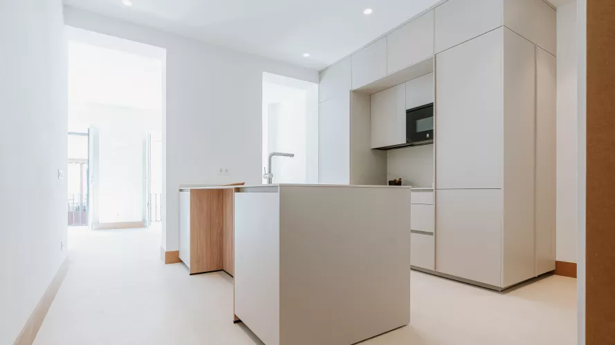 Cocina blanca con isla central y detalles en madera: amplitud, equilibrio y funcionalidad