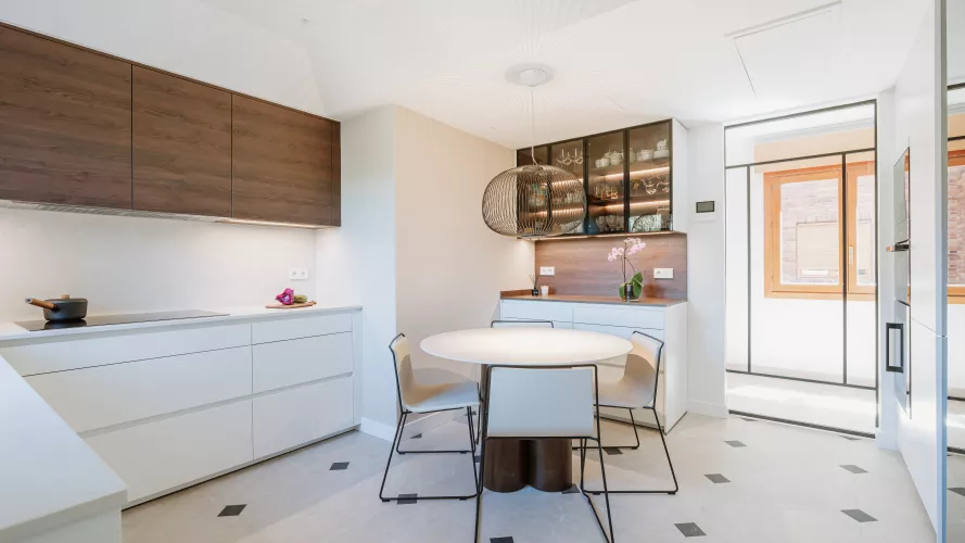 Cocina blanca con madera oscura y vitrinas iluminadas: equilibrio, calidez y funcionalidad