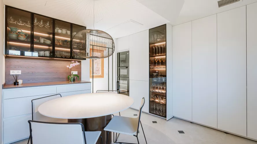 Cocina blanca con madera oscura y vitrinas iluminadas: equilibrio, calidez y funcionalidad