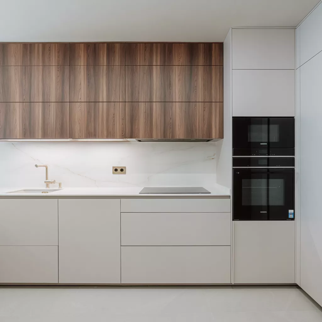 Descubre una cocina abierta con madera nogal y blanco cálido, barra integrada y diseño contemporáneo. Un proyecto real elegante, funcional y luminoso.